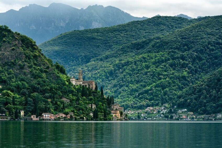 A lake with a church on a hill, surrounded by dense forest and mountains. 2