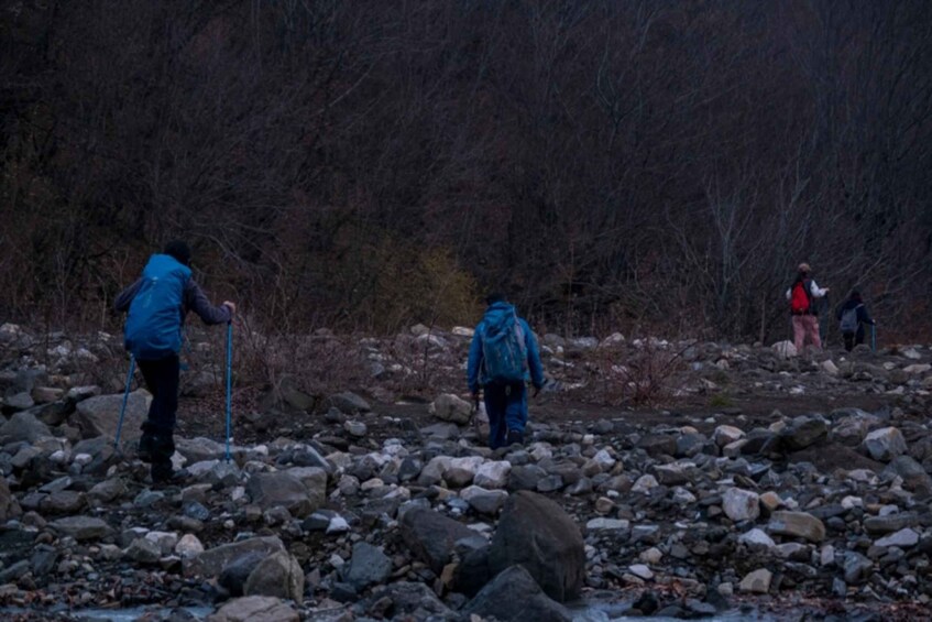 A rocky terrain with hikers using trekking poles. 5