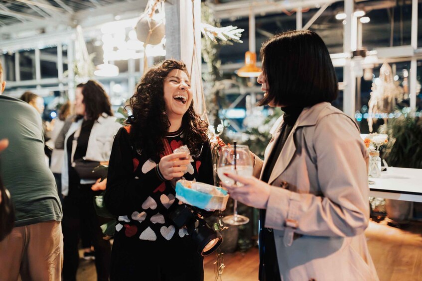Two people at an indoor event, one holding a drink and the other holding a wrapped gift. 5