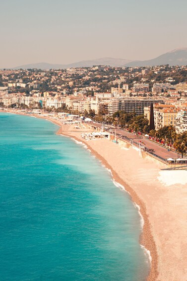 A coastal cityscape with a beach, buildings, and a mountain in the background. 4