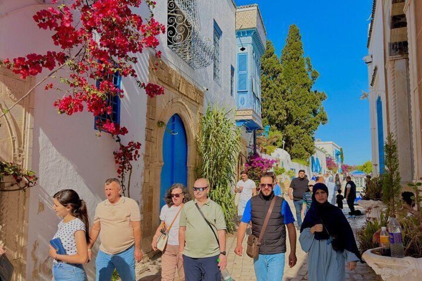 Un gruppo di persone che cammina su una strada con edifici bianchi e porte blu. 5