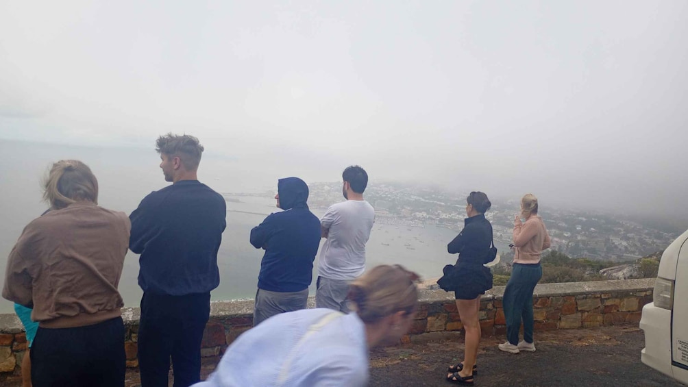 A group of people standing on a cliff overlooking a foggy coastline. 3