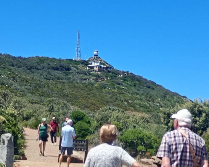 A group of people walking up a hill towards a hilltop structure with a tower. 4