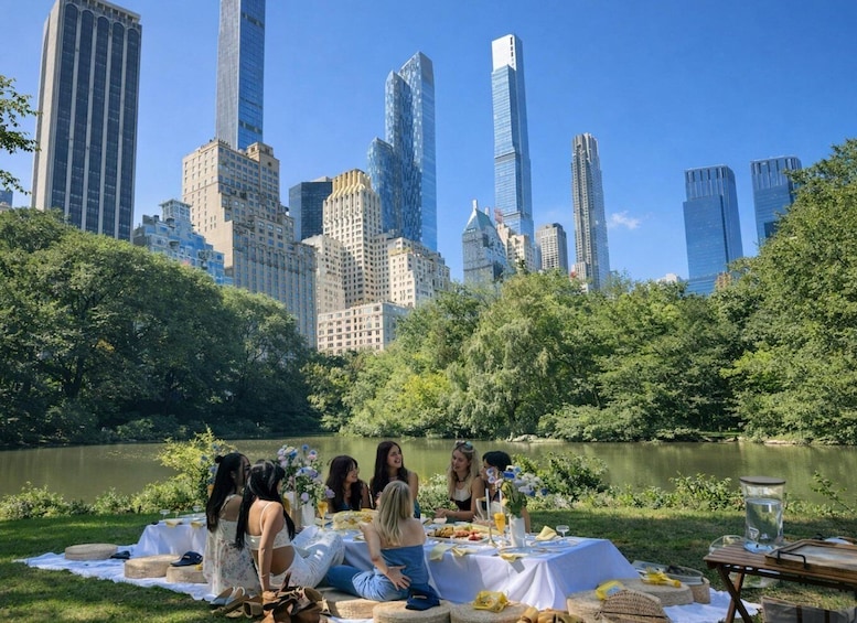 A group of people having a picnic by a lake with a city skyline in the background. 5