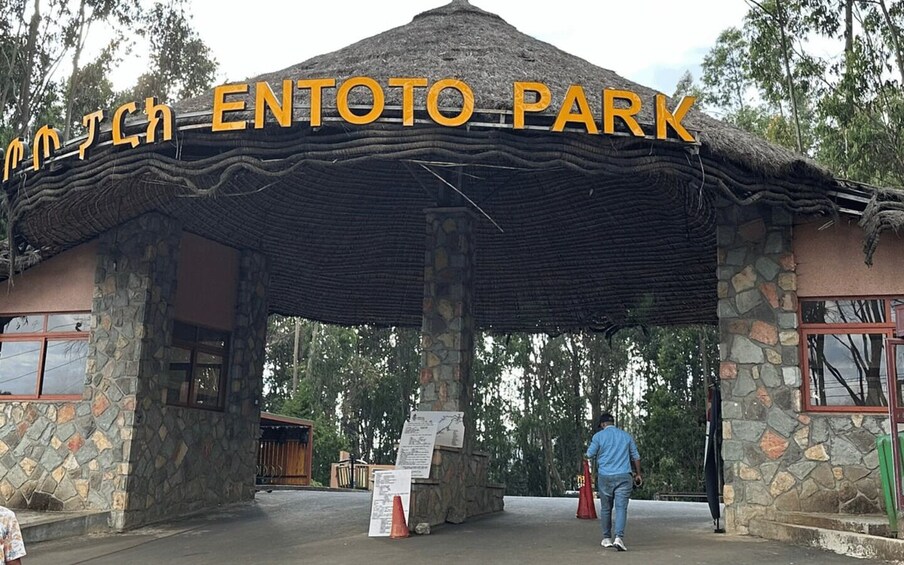 A stone structure with a thatched roof labeled 'ENTOTO PARK' and a person standing in front. 5