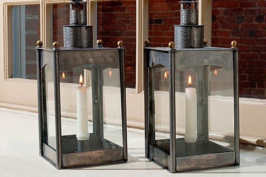 Two black lanterns with glass panels and candles inside, placed on a white surface. 2