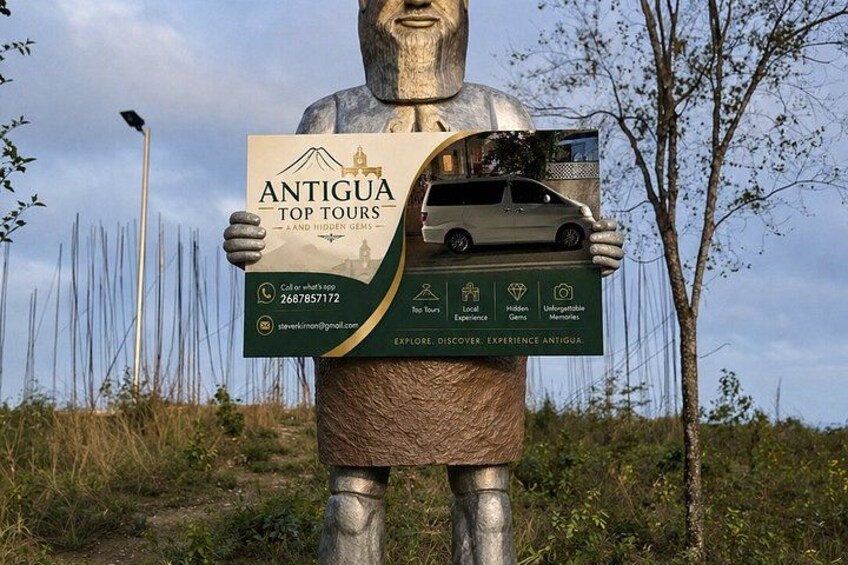 A statue holding a sign for Antigua Top Tours, with a car model on top. 2