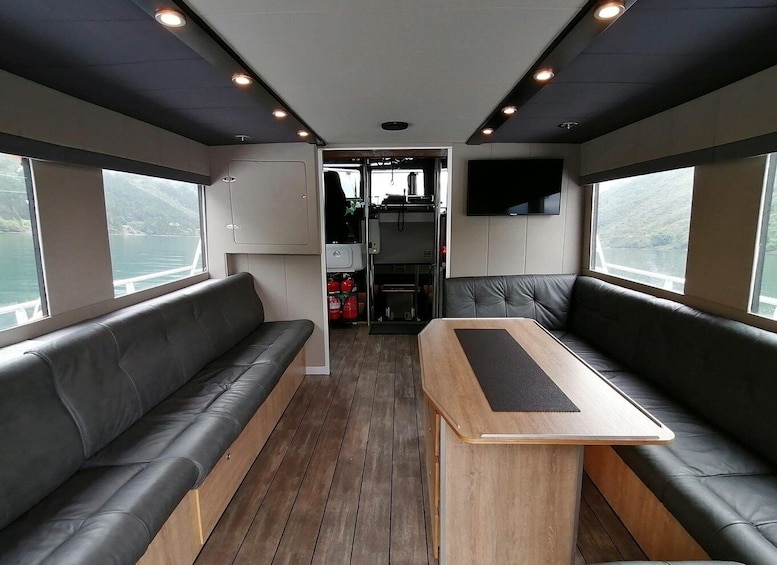 A cabin interior with leather seating, a central table, and a mounted TV. 3