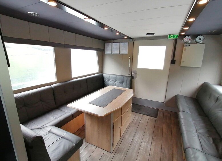 A compact, modern interior with leather seating, a wooden table, and a small kitchenette. 2