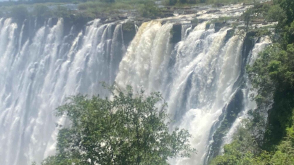 A large waterfall cascading down a cliff surrounded by greenery. 2