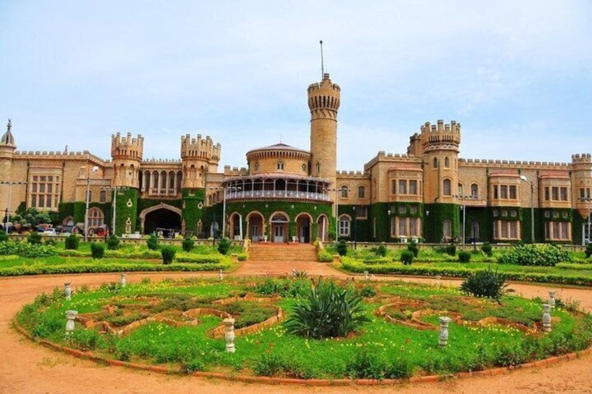 Un edificio in stile castello con una torre centrale, circondato da un giardino formale caratterizzato da motivi geometrici e statue. 4