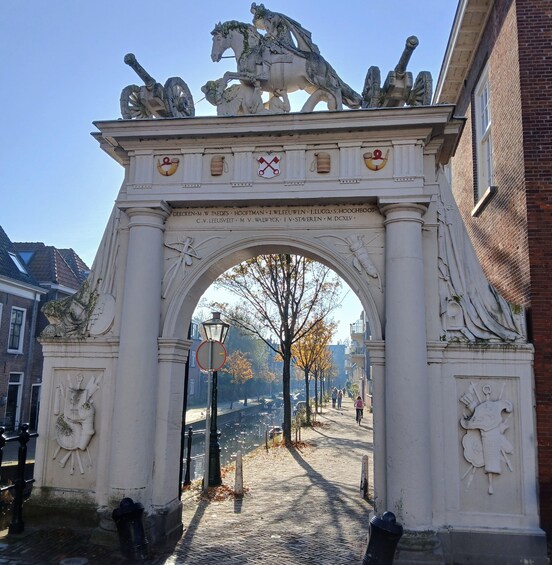 An ornate stone archway with horse statues and coats of arms, leading to a cobblestone street. 4