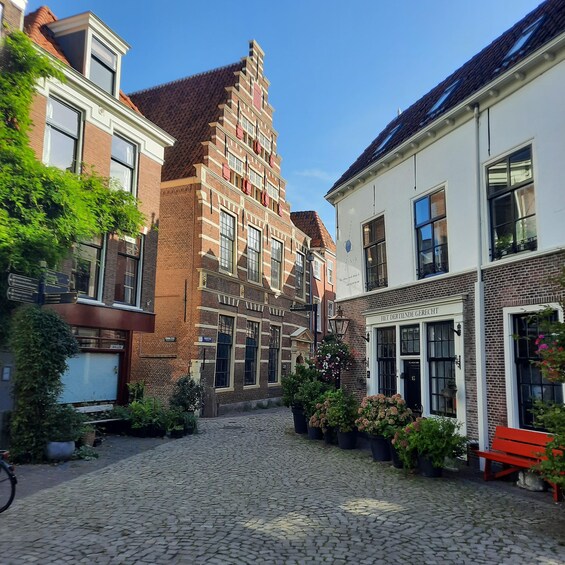 A cobblestone street lined with historic buildings, a red bench, and potted plants. 3