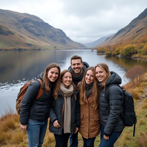 A group of people standing by a lake with mountains in the background. 2