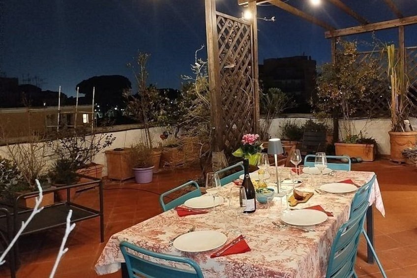 Een buitenterras met een tafel voor vier personen, omringd door potplanten en een houten pergola. 1