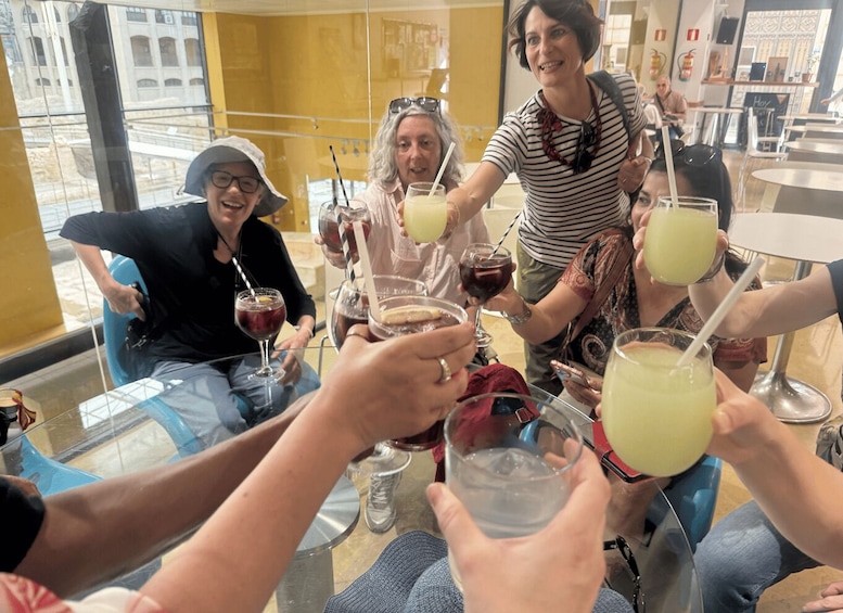 A group of people sitting at a table, toasting with drinks. 4