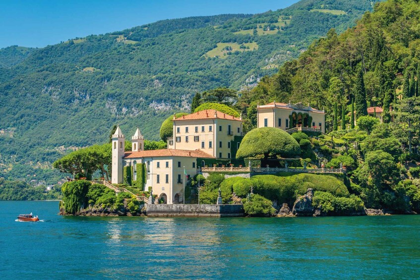 A lakeside villa with a tower, surrounded by lush greenery and hills. 2