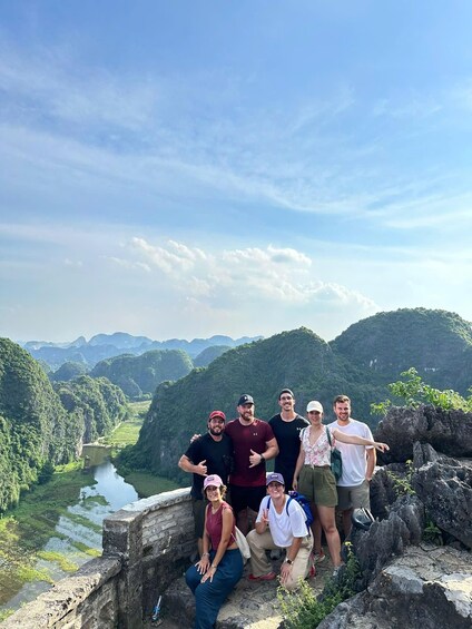 A group of people on a rocky overlook with a river and mountains in the background. 4