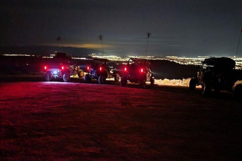 Off-road vehicles at night with city lights in the background. 4