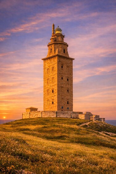 A lighthouse on a grassy hill with a sunset in the background. 3