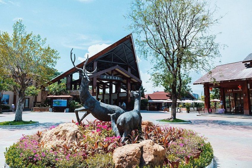 Una escultura de ciervo en un área ajardinada, con edificios al fondo. 3