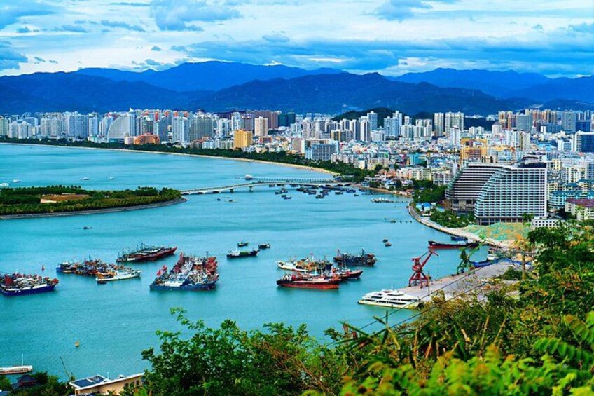 Un paisaje urbano costero con un río, barcos y montañas al fondo. 4