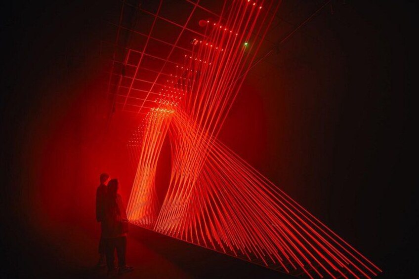 A person standing in a dimly lit area with red laser lights. 2
