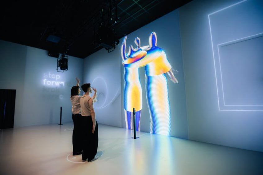 A person interacting with a digital display featuring a human figure. 3
