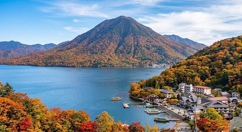 A mountain lake with autumn foliage, boats, and buildings. 3