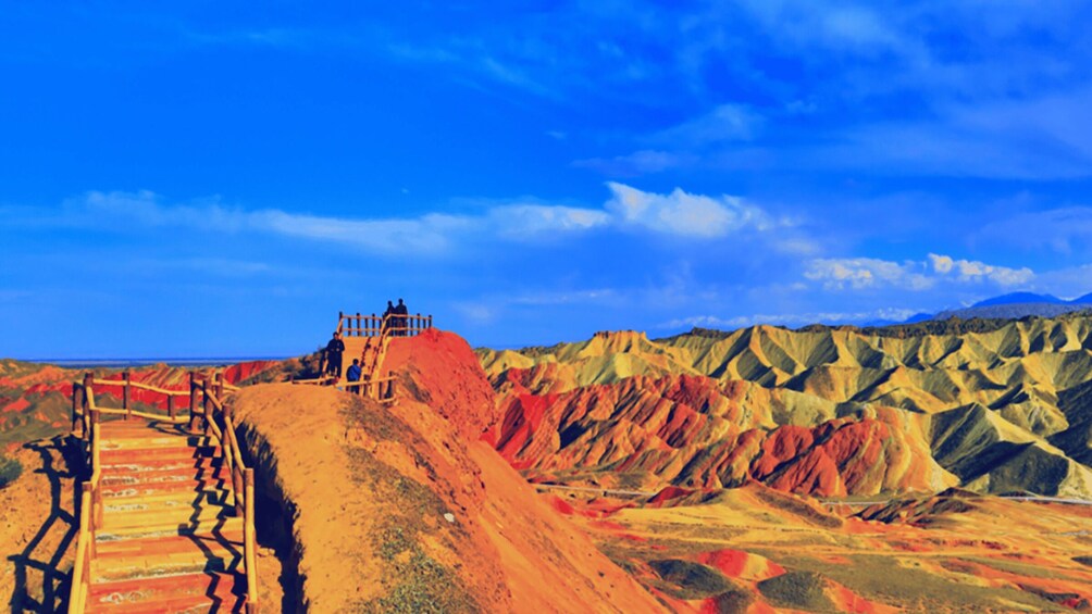 A desert landscape with a wooden staircase leading up a hill, a wooden fence, and a clear blue sky. 2