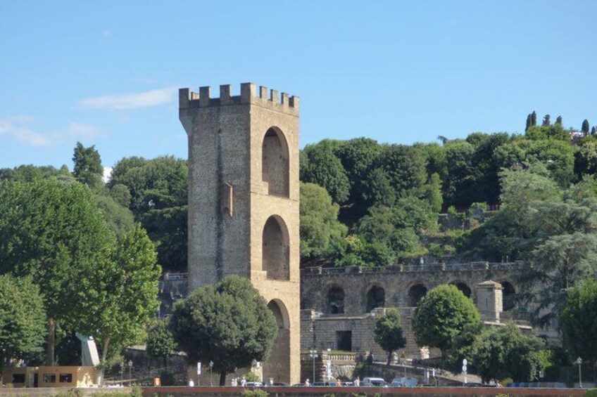 Ein historischer SteinTurm mit rundbogenförmigen Fenstern, einer Brücke und üppigem Grün. 2