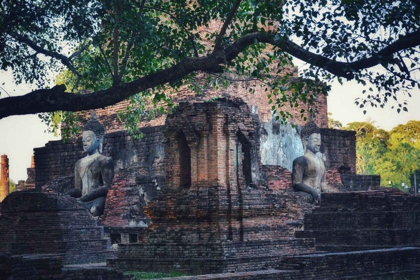 Ancient ruins with large stone statues and a tree overhead. 5