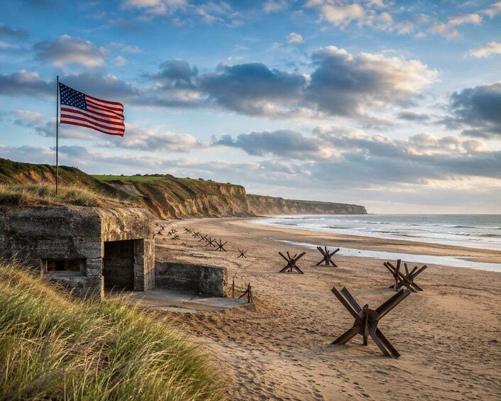 A beach with a flag, a bunker, and wooden stakes. 1