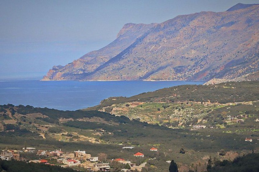 Paesaggio costiero con montagne, un villaggio e una distesa d'acqua. 5