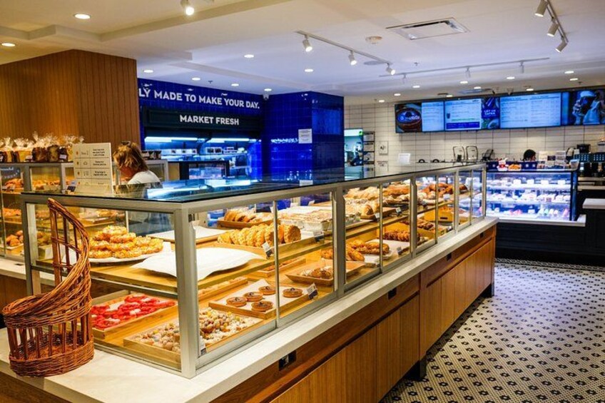 Mostrador de panadería con distintos productos horneados, un panel de menú digital y una zona de mostrador. 5