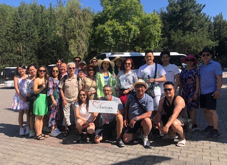 A group of people posing for a photo in an outdoor setting with trees and a bus in the background. 4