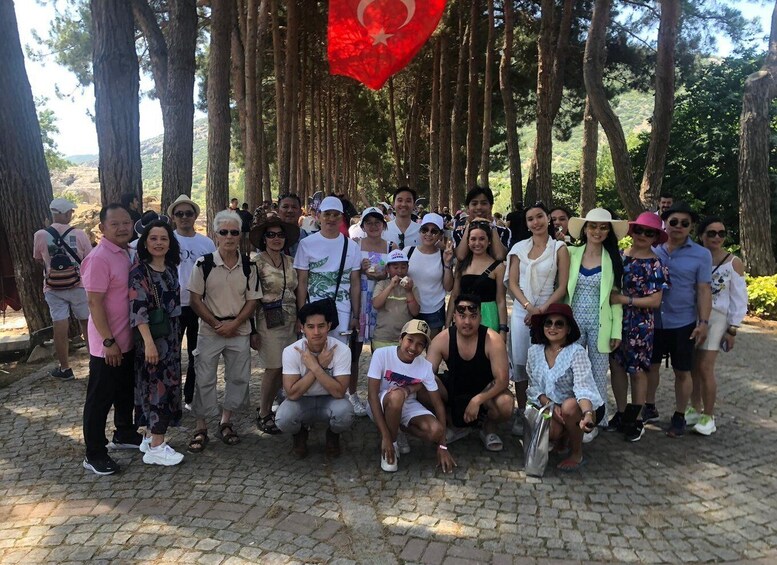 A group of people posing for a photo in a wooded area with a red flag. 5