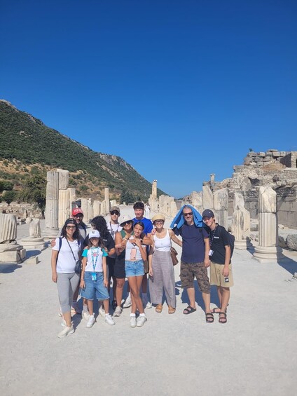 A group of people posing in front of ancient ruins with a clear blue sky in the background. 3