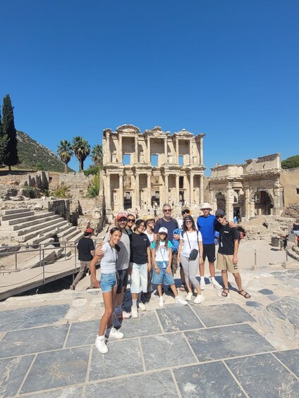 A group of people standing in front of ancient ruins with columns and steps. 1