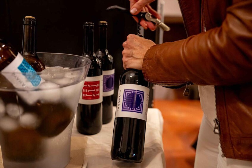 A person opening a bottle of wine with a corkscrew. 2