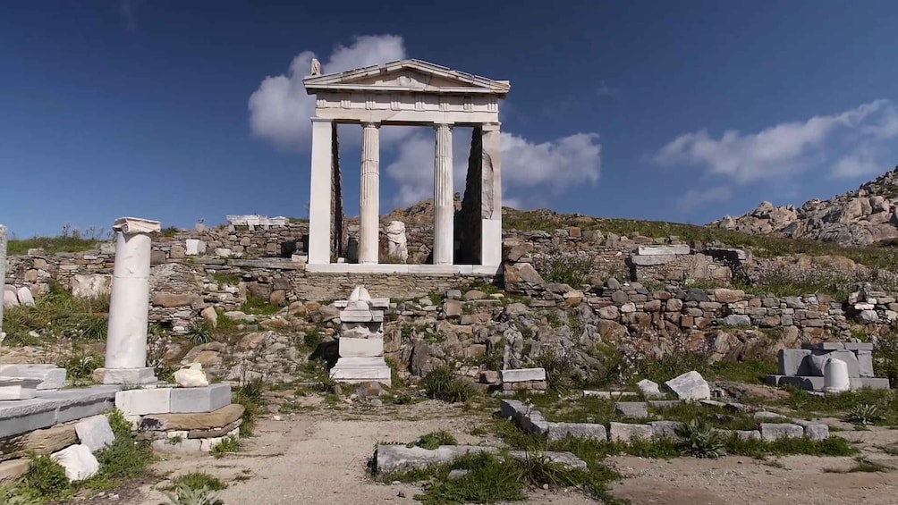Ancient ruins with a prominent white temple structure on a hillside. 2