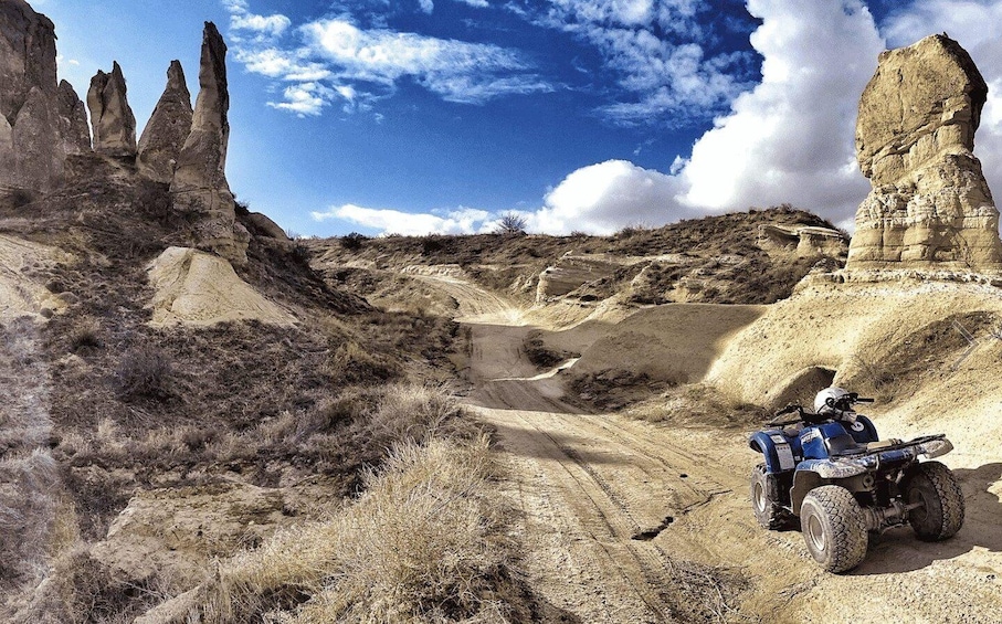 A desert landscape with rock formations and a blue off-road vehicle. 2