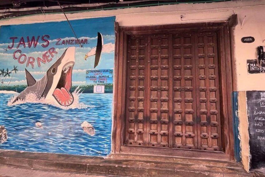 En mural af en haj med teksten 'JAWS CORNER' og en trædør med et gittermønster. 5
