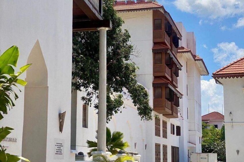 Un edificio bianco con numerosi balconi e un tetto in tegole rosse, immerso nel verde. 3