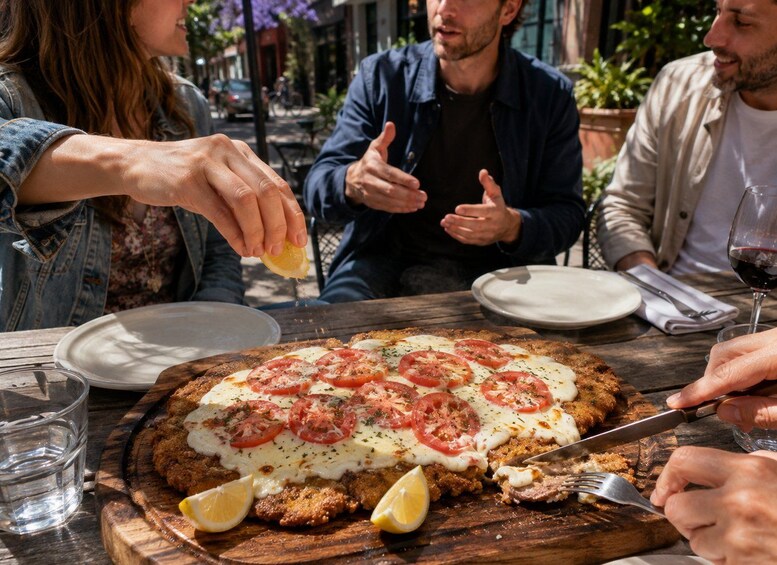 A group of people dining outdoors with a pizza topped with tomatoes and cheese. 2