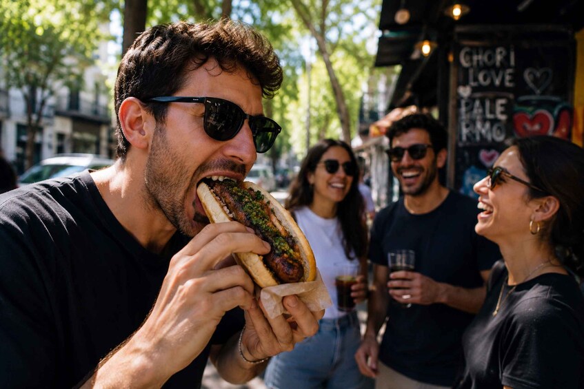 A person eating a hot dog outdoors with a chalkboard in the background. 2