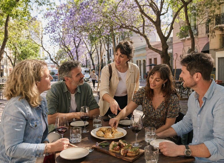 A group of people dining outdoors at a table with food and drinks. 1