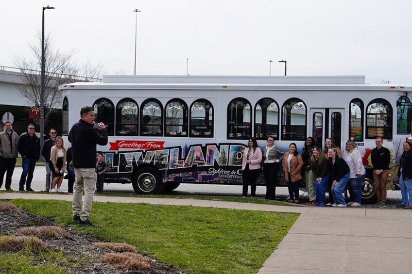 A group of people gathered around a bus with a 'Greetings from' sign. 2