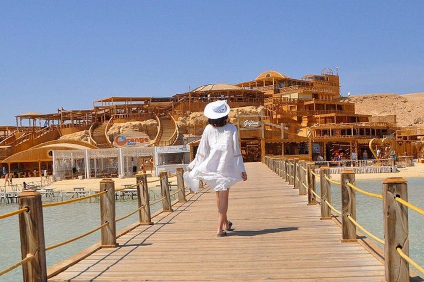 Un molo di legno che conduce a una spiaggia, con un resort sullo sfondo. 1