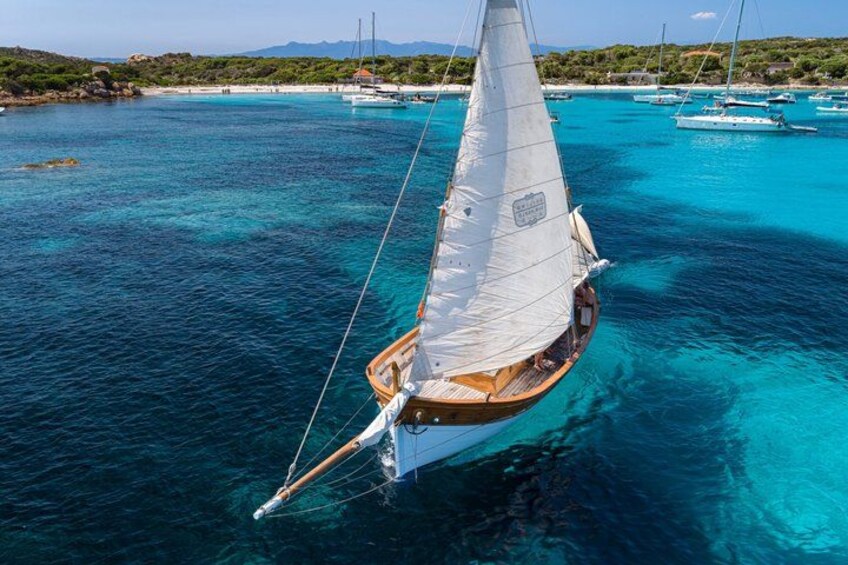 Un voilier sur des eaux turquoise, avec un paysage côtier en arrière-plan. 4